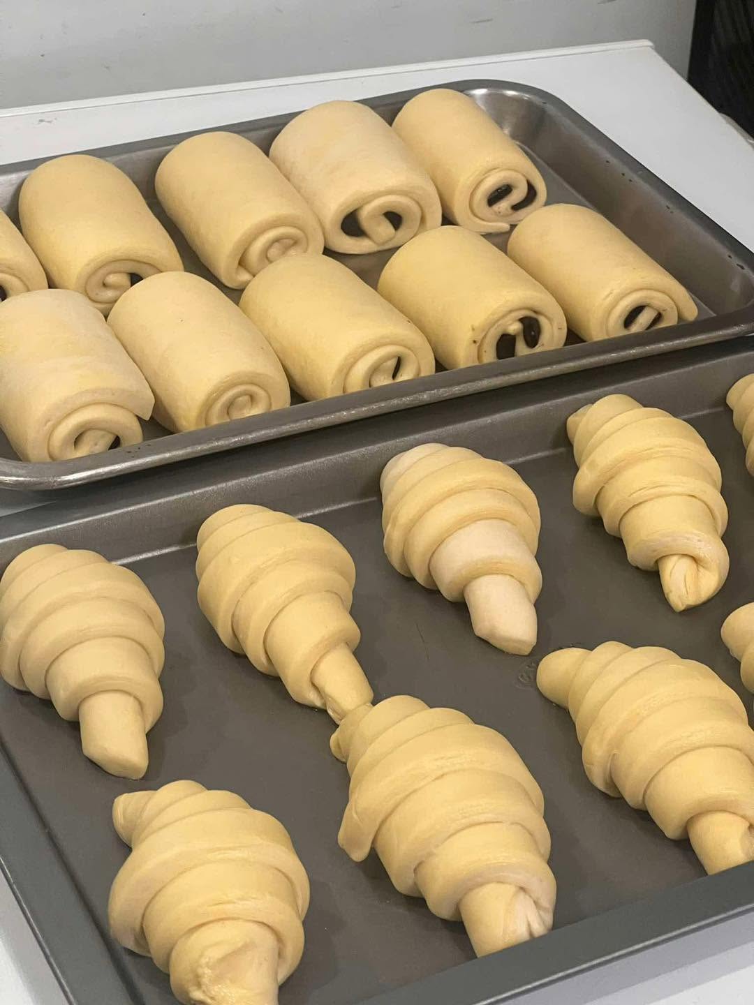 Raw croissant dough shaped and trayed by hand in The Café Commissary kitchen